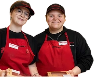 Two grocery store employees in uniform holding boxed goods.