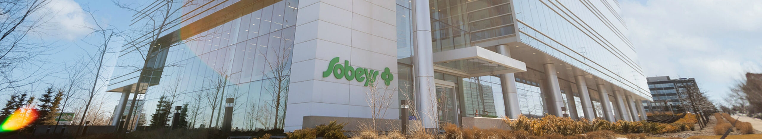 Sobeys corporate office building with glass exterior and landscaped entrance in daylight.