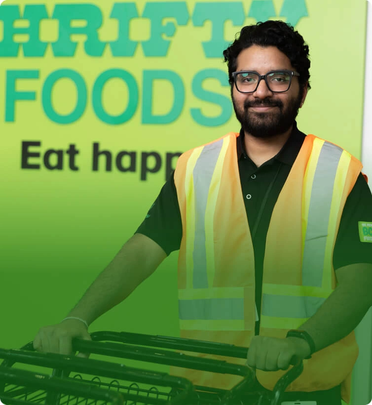 A Thrifty Foods team member in a high-visibility vest holding shopping carts.