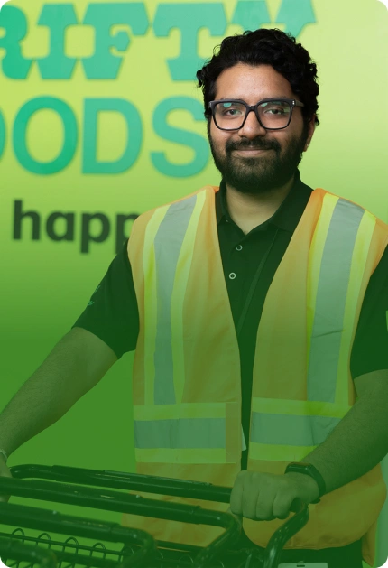 A Thrifty Foods team member in a high-visibility vest holding shopping carts.
