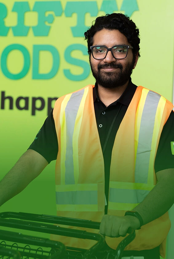 A Thrifty Foods team member in a high-visibility vest holding shopping carts.